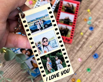 Op de afbeelding: Een heldere acryl sleutelhanger met drie foto's in een filmstrip ontwerp. De foto's tonen mensen die buiten poseren. De sleutelhanger heeft een metalen ring en sluiting. De tekst "I LOVE YOU" staat onderaan.