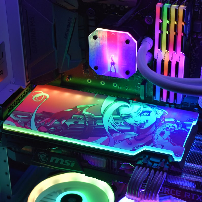 May include: A computer's internal components are illuminated with colorful LED lights. A graphic card features a cartoon character design with a pink and green color scheme. The MSI logo is visible. Other components include RAM sticks and a water cooling block.