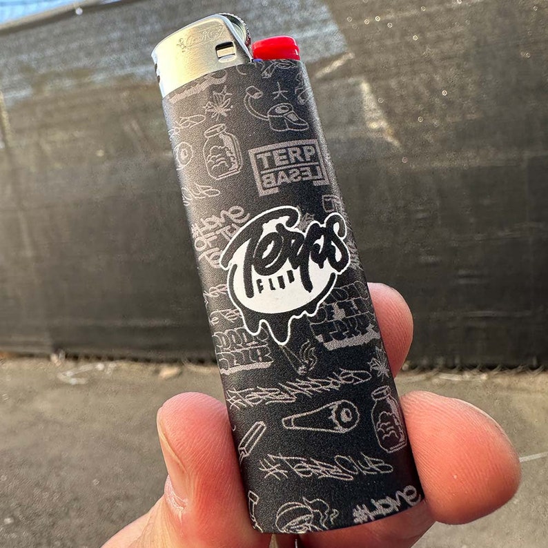 May include: Black and white lighter with a graphic design featuring the words "Terps Club" and "Terp Based".