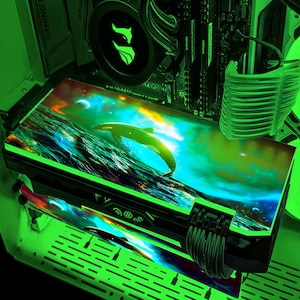 May include: A custom computer component with a vibrant design featuring a breaching orca in a sea scene with a starry sky. The component has a green glow and is installed inside a computer case.