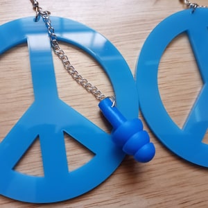 May include: A pair of blue peace sign earrings with a silver chain and a blue earplug charm.