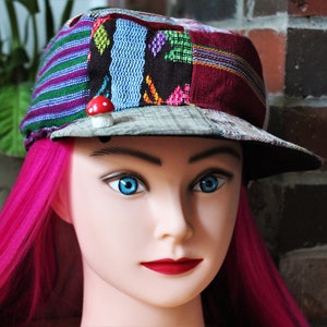 May include: A mannequin head with pink hair wearing a multi-colored patchwork cap with a small red mushroom pin.