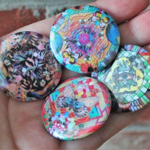 Könnte beinhalten: Vier bunte runde Knöpfe mit psychedelischen Mustern mit Schmetterlingen, Augen und geometrischen Designs.