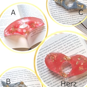 May include: Three resin hair clips labeled A, B, and C. Clips A and C are translucent red with gold leaf flakes, while clip B is translucent gray with gold leaf flakes. Clips A and C are crescent-shaped, and clip B is a multi-pointed shape.