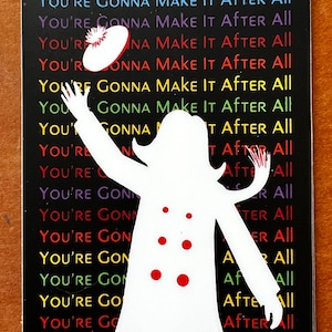 May include: A white silhouette of a person wearing a hat and coat with red buttons, standing in front of a black background with the repeated text "You're Gonna Make It After All" in rainbow colors.