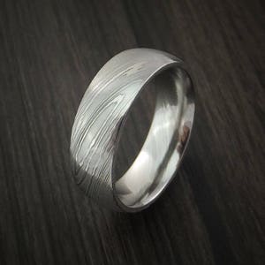 May include: A silver wedding band with a brushed metal finish and a unique patterned design.