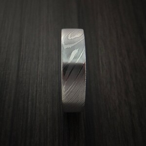May include: A silver ring with a unique, swirling pattern. The ring is made of metal and has a polished finish.