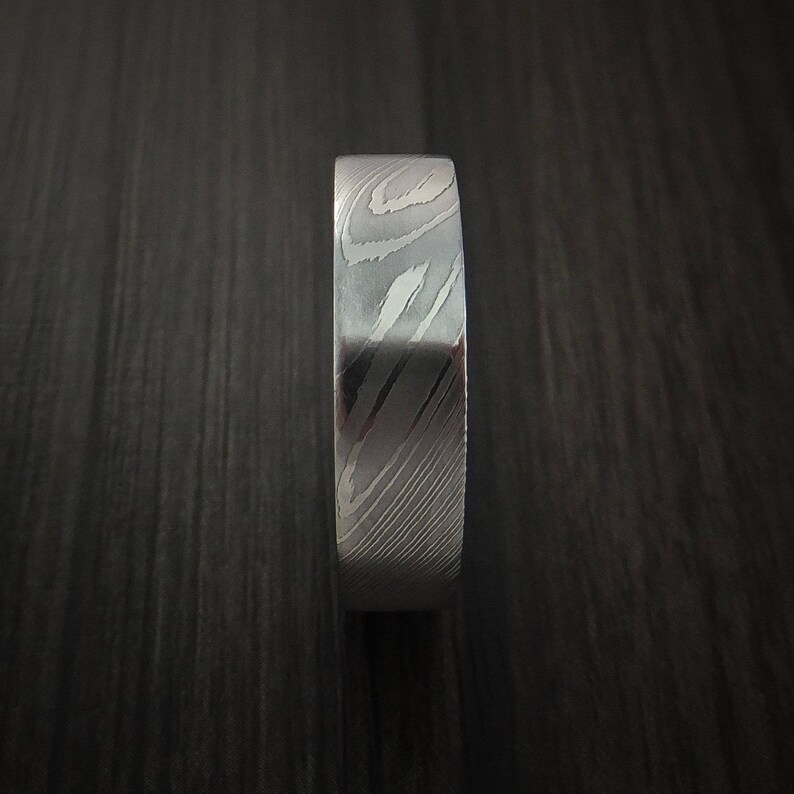 May include: A silver ring with a unique, swirling pattern. The ring is made of metal and has a polished finish.
