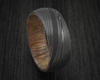 Damascus steel ring with whiskey barrel interior wood sleeve custom made
