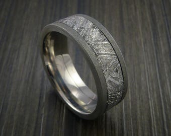 May include: A silver ring with a band of meteorite material. The meteorite material has a unique pattern of lines and swirls.
