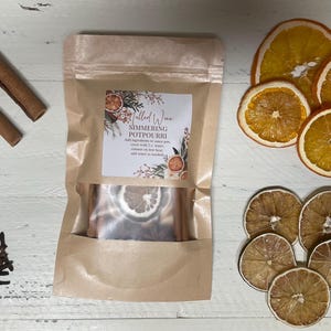 May include: A brown paper bag filled with dried orange slices, cinnamon sticks, star anise, and cloves. The bag has a label that reads "Mulled Wine Simmering Potpourri".