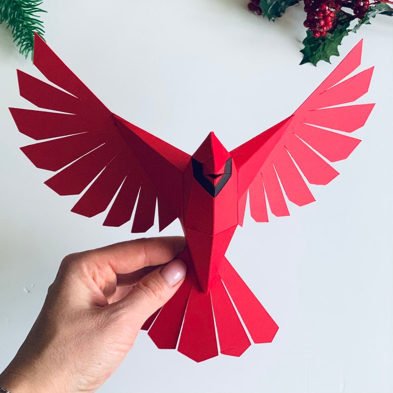 Pu&ograve; includere: Ciondolo di uccello cardinale rosso di carta con occhi e becco neri. L'uccello &egrave; in volo con le ali spiegate.
