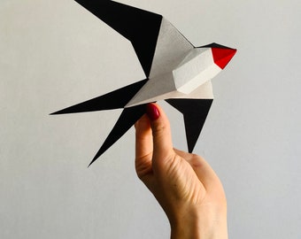 Pode incluir: Uma andorinha de origami de papel preto e branco com um bico vermelho. A andorinha é segurada na mão contra um fundo branco. A imagem inclui o texto "PDF" e "DXF" em texto preto sobre quadrados brancos.
