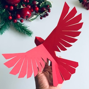 Pu&ograve; includere: Un ornamento di carta rosso a forma di cardinale con ali piegate, un progetto di artigianato di carta 3D.