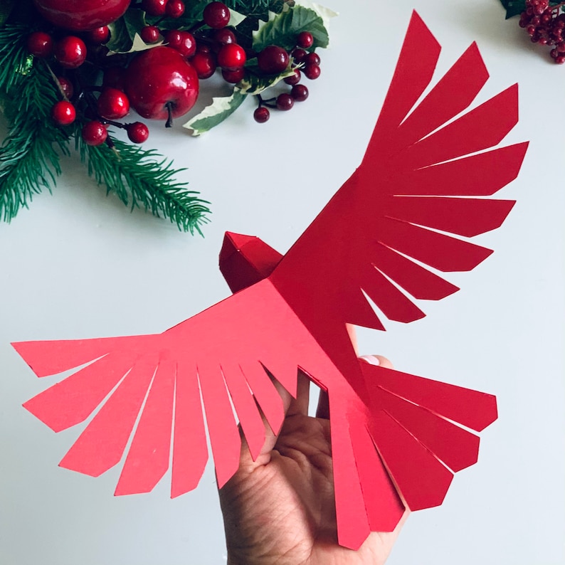 Pu&ograve; includere: Un ornamento di carta rosso a forma di cardinale con ali piegate, un progetto di artigianato di carta 3D.