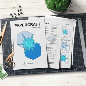 May include: Papercraft snowflake template with instructions. The template features a blue and white snowflake design with geometric shapes. The instructions include diagrams and text.