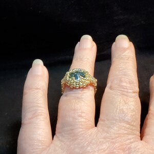 May include: A gold ring with a dark blue gemstone set in a beaded design.