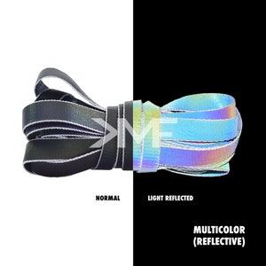May include: A close-up of a black and silver shoelace with a reflective, iridescent finish. The shoelace is shown in both normal and light reflected conditions. The text "MULTICOLOR (REFLECTIVE)" is visible below the image.