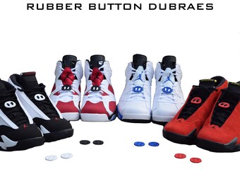 May include: A set of six rubber button dubraes in red, white, and blue. The dubraes are shown on three pairs of trainers. The trainers are a pair of black and white trainers, a pair of red and white trainers, and a pair of white trainers.