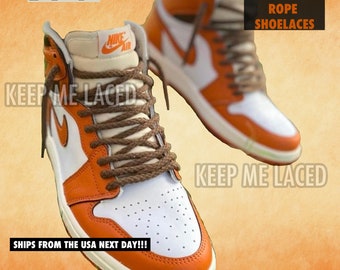 May include: A pair of orange and white sneakers with brown rope laces. The laces are tied in a unique way, with the ends of the laces tucked into the eyelets. The sneakers have the text "KEEP ME LACED" printed on the side. The text "THIN BRAIDED ROPE SHOELACES" is printed on a black rectangle in the upper right corner of the image. The text "SHIPS FROM THE USA NEXT DAY!!!" is printed in the lower left corner of the image.