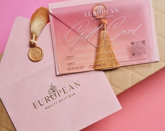 May include: A gift card from European Beauty Boutique with a gold tassel and a matching pink envelope. The gift card is in a clear sleeve with the words "Gift Card" in elegant script. The envelope is sealed with a gold wax seal.