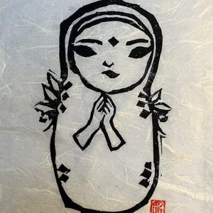 May include: Black and white ink drawing of a person with a hood, hands clasped in prayer, and a third eye on their forehead. The drawing is on a textured white paper with a red stamp in the lower right corner.