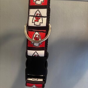 Puede incluir: Un collar de perro rojo, blanco y negro con un patr&oacute;n repetido del logotipo de los Kansas City Chiefs. El collar tiene un anillo en D plateado y una hebilla de pl&aacute;stico negra.