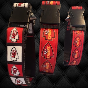 Puede incluir: Tres collares de perro rojos, blancos y dorados con hebillas negras. Los collares presentan el logotipo de los Kansas City Chiefs y la palabra "Chiefs".