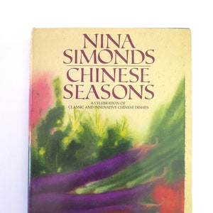 May include: A book cover with a watercolor illustration of eggplant, peppers, and other vegetables. The title is "Nina Simonds Chinese Seasons: A Celebration of Classic and Innovative Chinese Dishes."
