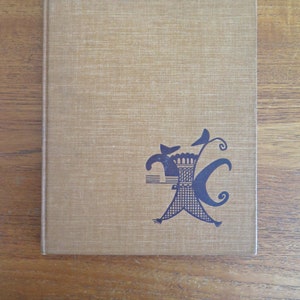 Puede incluir: Un libro de tapa dura marrón con una ilustración en blanco y negro de una figura estilizada en la portada.