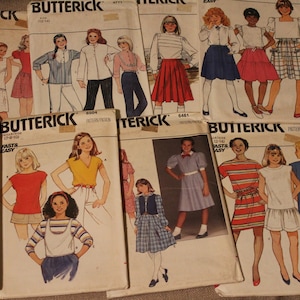 May include: A collection of vintage sewing patterns for children's clothing. The patterns are from the Butterick brand and feature various styles, including dresses, skirts, and tops. The patterns are printed on paper and have illustrations of the finished garments.