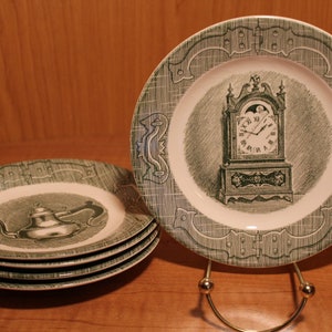 May include: Four green and white ceramic plates with a green and white design. The plates feature a clock and a teapot.