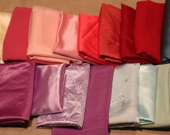 May include: A collection of 15 fabric swatches in various shades of pink, red, purple, blue, and green. The swatches are arranged in a row, with the lightest shades on the left and the darkest shades on the right.