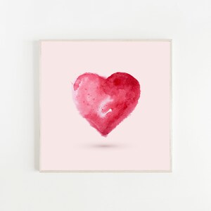 May include: A framed watercolor painting of a red heart on a light pink background.