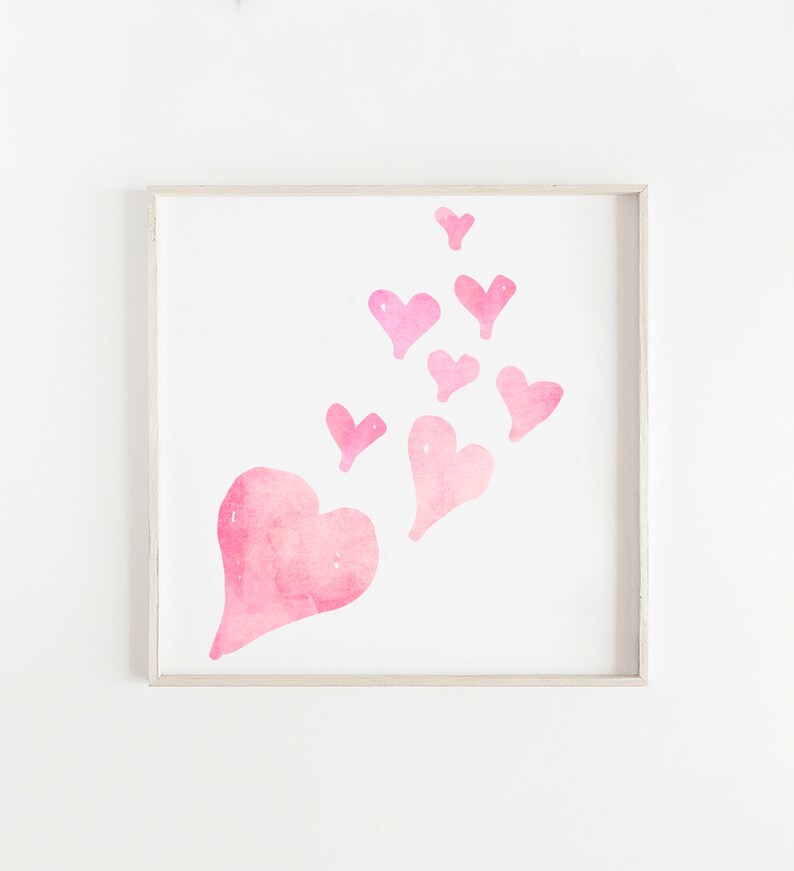 May include: A framed print with a watercolor painting of pink hearts. The hearts are arranged in a cluster, with the largest heart at the bottom and the smaller hearts floating upwards.