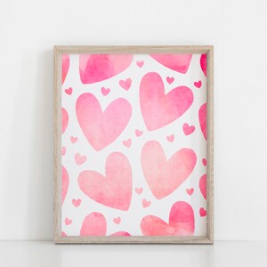 May include: A framed print featuring a pattern of pink watercolour hearts on a white background.