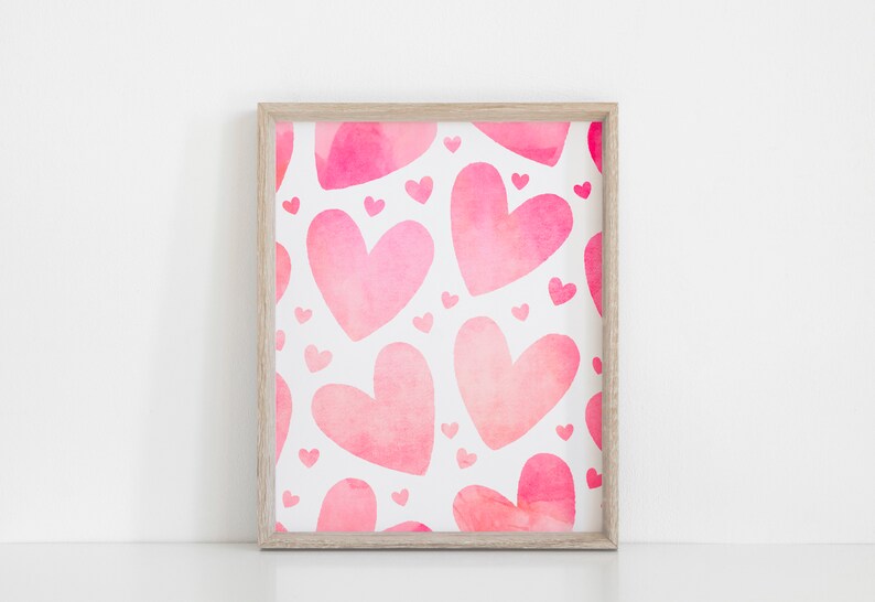 May include: A framed print featuring a pattern of pink watercolour hearts on a white background.