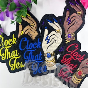 May include: Embroidered patches featuring hands adorned with rings and watches, with the text "Clock That Tea" in various colors. The patches have black backgrounds and are surrounded by purple and pink flowers.