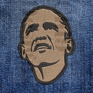 May include: An embroidered patch of a person's face, in brown and black. The person is looking upwards with their mouth slightly open.