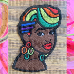 Könnte beinhalten: Gestickter Aufnäher mit einem stilisierten Porträt einer schwarzen Frau mit regenbogenfarbenem Haar und buntem Schmuck. Die Frau trägt ein braunes Oberteil und hat rote Lippen.
