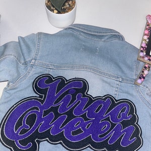 May include: A light blue denim jacket with a purple and black embroidered patch that says "Virgo Queen".
