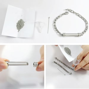 May include: A silver bracelet with a small, cylindrical container attached. The container is open and a small funnel and a metal tool are nearby. A small pile of gray powder is on a white piece of paper.