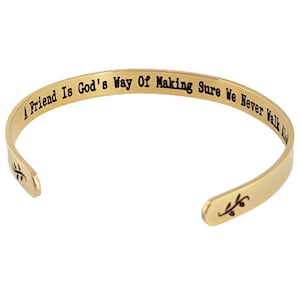 May include: Gold-toned bangle bracelet with the inscription "A Friend Is God's Way Of Making Sure We Never Walk Alone".