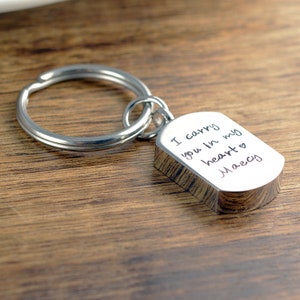 May include: Silver keyring with a rectangular tag engraved with the words "I carry you in my heart" and the name "Maecy".