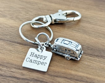 May include: Silver keychain with a small camper charm and a square tag that says "Happy Camper".