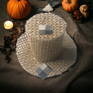 May include: A brown and white woven hat with a black and white checkered design. The hat is sitting on a brown surface.