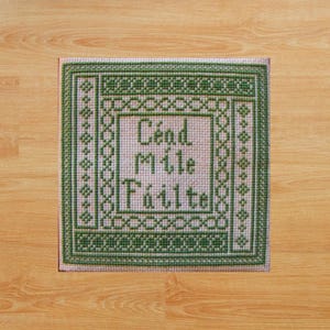 May include: Green and white cross-stitch embroidery with a Celtic knot border and the text "Cead Mile Failte" in the center.