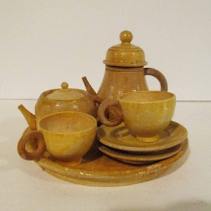 May include: A wooden tea set with a teapot, creamer, sugar bowl, two cups, and saucers. The set is painted in shades of brown and beige.