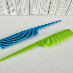 May include: Two plastic combs, one blue and one green, with long, thin handles. The combs have a textured design and are ideal for detangling hair.