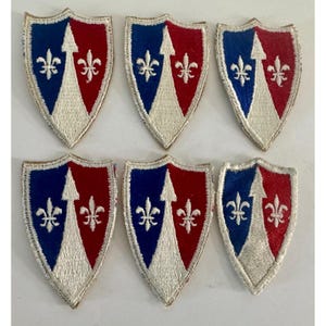 May include: Six embroidered shield patches. Each patch features a blue and red design with a white arrow and fleur-de-lis. The patches are in a shield shape with a white border.
